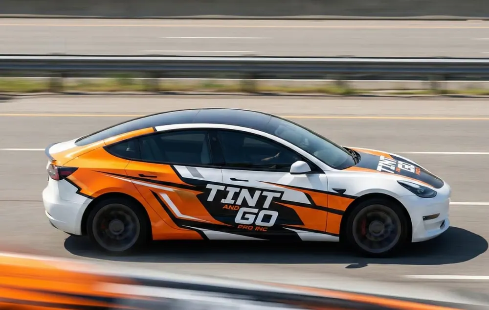 Tesla Model 3 in an orange and white printed Tint and Go Pro livery on a race circuit