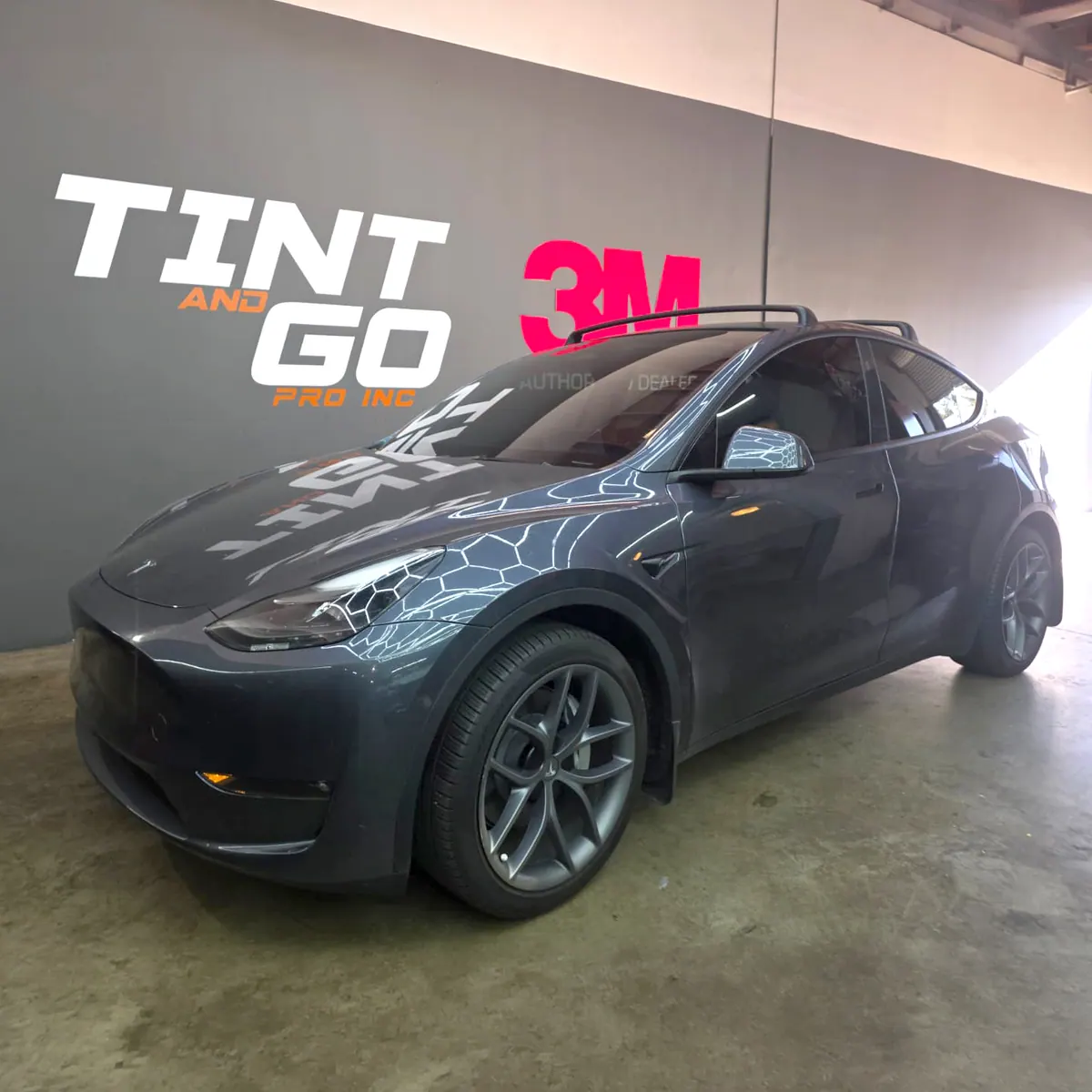Charcoal Tesla Model Y with tinted glass in the Tint & Go Pro bay