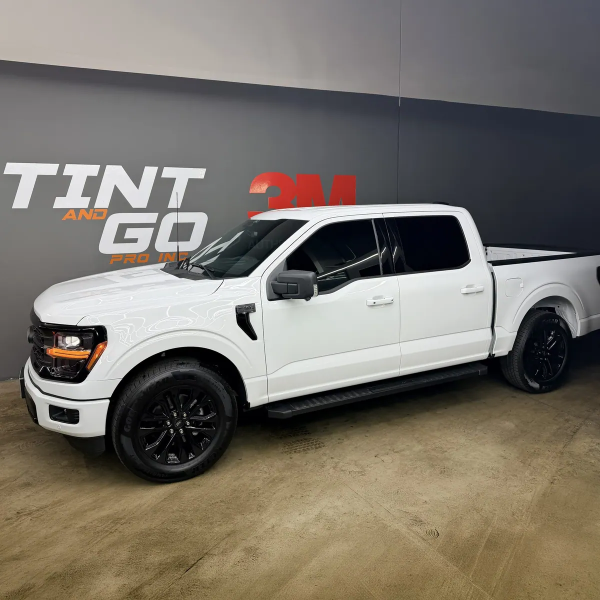 White Ford F-150 pickup with tinted windows and black wheels in the Corona studio