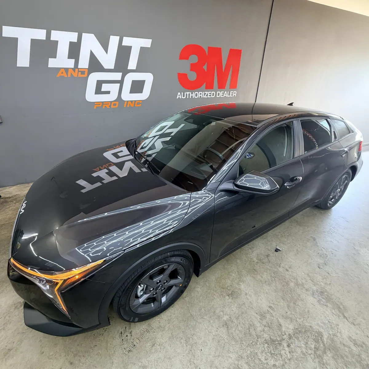 Dark grey sport sedan with a polished finish inside the Tint & Go Pro studio