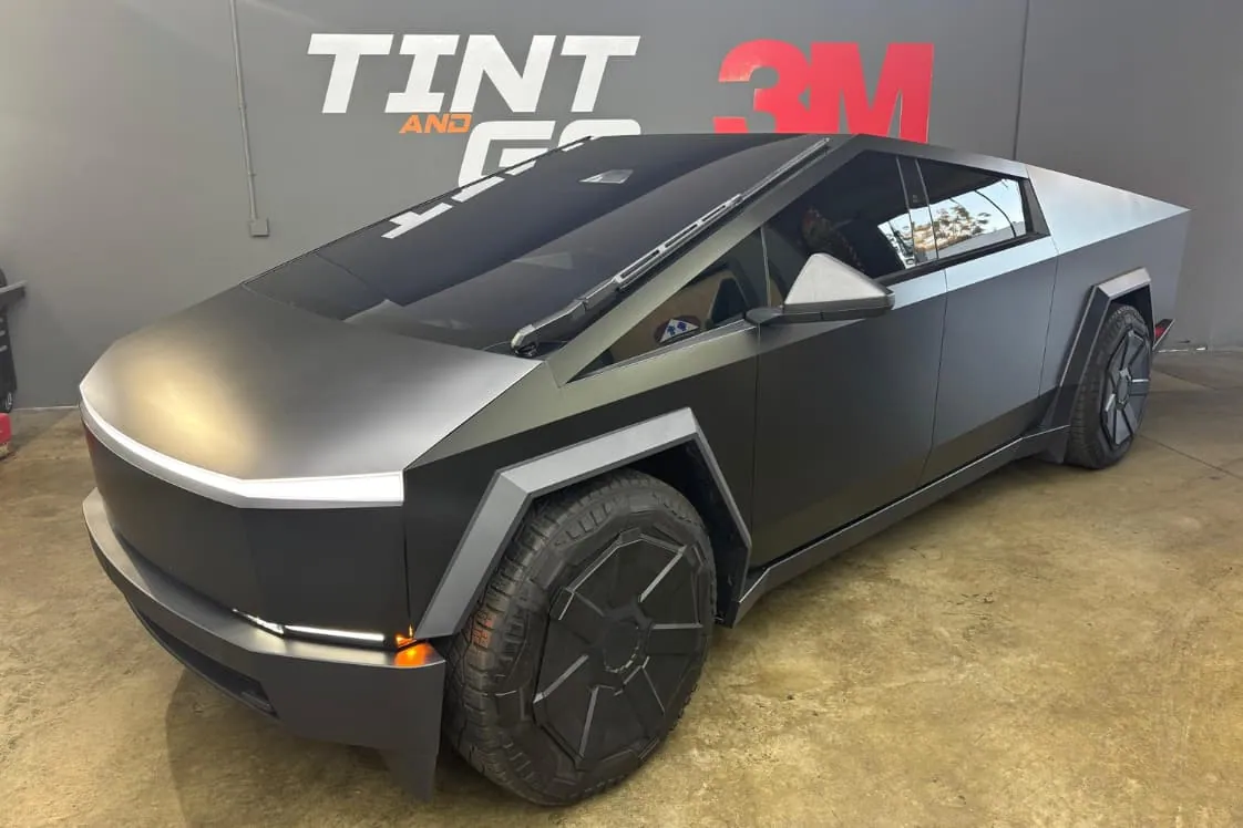 Tesla Cybertruck parked inside the Tint & Go Pro shop bay in front of the Tint and Go and 3M wall graphics